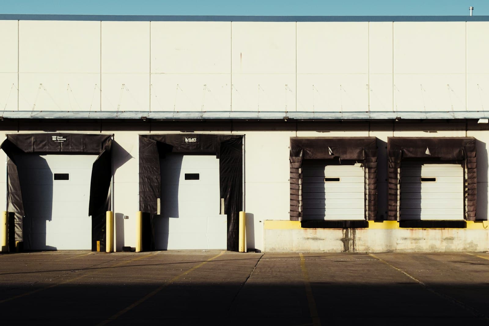 A row of loading dock bays with dock seals on the side of an industrial warehouse building in warm afternoon light.